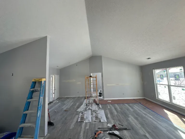 Interior of a room under renovation with a ladder, scaffolding, and construction materials on the floor.