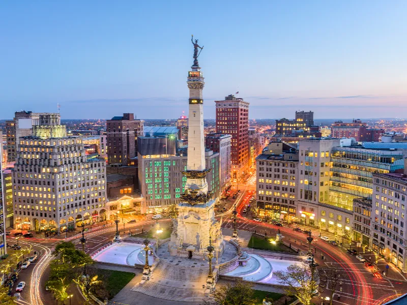 Monument Circle with the Soldiers and Sailors Monument surrounded by city buildings at dusk.