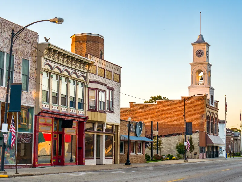 Small town street with historic brick buildings and a clock tower at sunset.