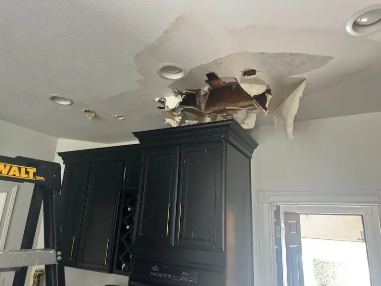 Ceiling with large water damage and a hole above kitchen cabinets.